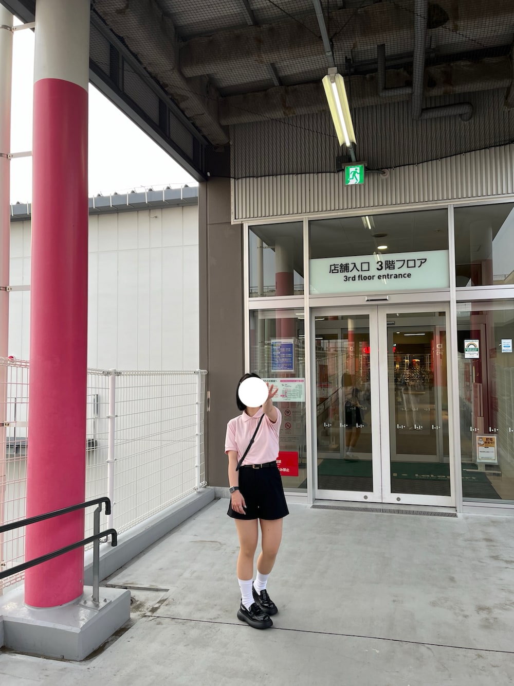 ピンク系のポロシャツ、ブラック系のショルダーバッグ、ブラック系のローファーを着用したレディースの春コーディネートの2枚目の写真