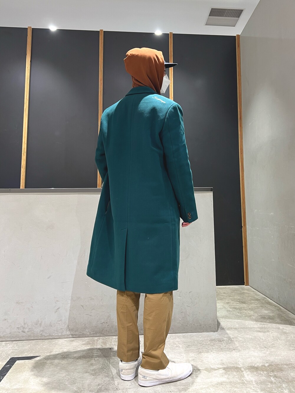 ブラウン系のパーカー、ブラウン系のその他パンツ、グリーン系のチェスターコートを着用したメンズの秋コーディネートの4枚目の写真