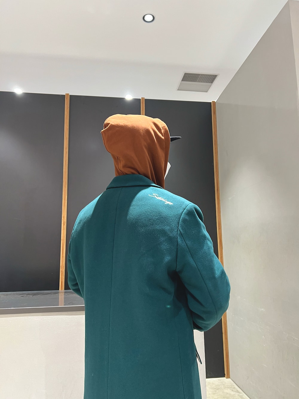 ブラウン系のパーカー、ブラウン系のその他パンツ、グリーン系のチェスターコートを着用したメンズの秋コーディネートの2枚目の写真