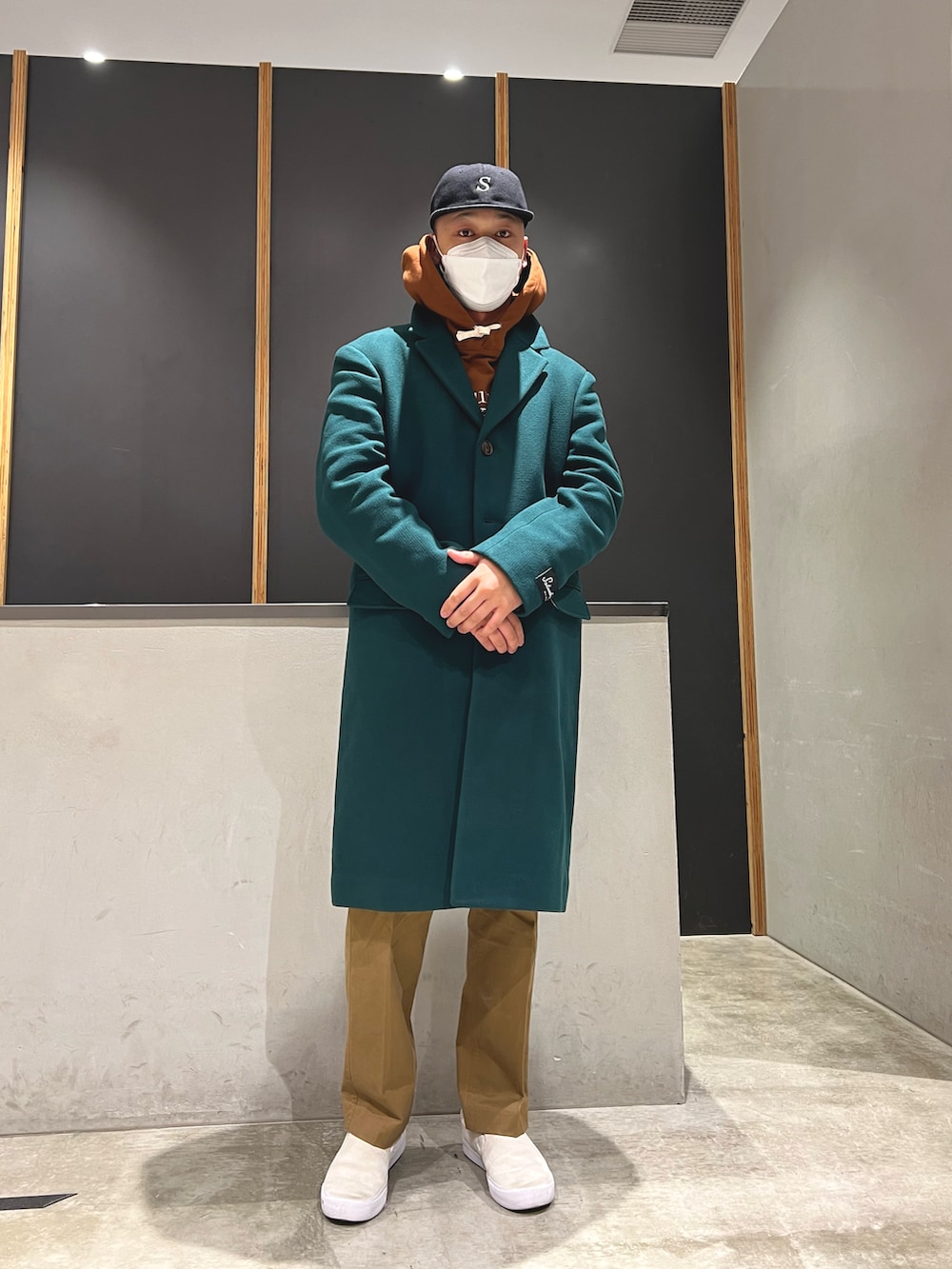 ブラウン系のパーカー、ブラウン系のその他パンツ、グリーン系のチェスターコートを着用したメンズの秋コーディネートの5枚目の写真