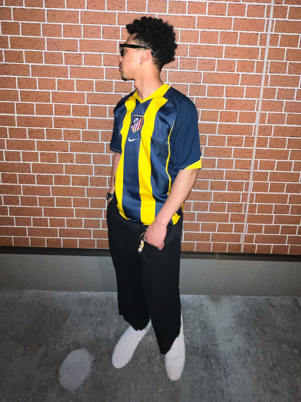 ブラック系のチノパンツ、ホワイト系のスニーカー、イエロー系のジャージを着用したメンズの春コーディネートの4枚目の写真