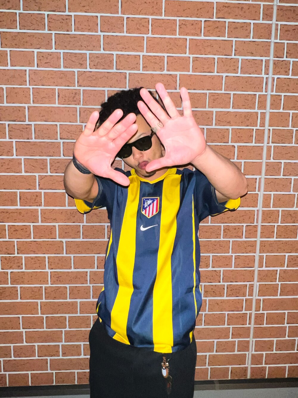 ブラック系のチノパンツ、ホワイト系のスニーカー、イエロー系のジャージを着用したメンズの春コーディネートの2枚目の写真