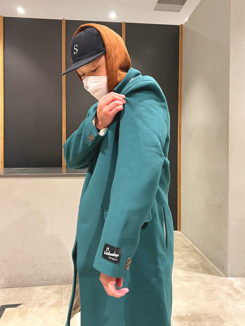 ブラウン系のパーカー、ブラウン系のその他パンツ、グリーン系のチェスターコートを着用したメンズの秋コーディネートの3枚目の写真