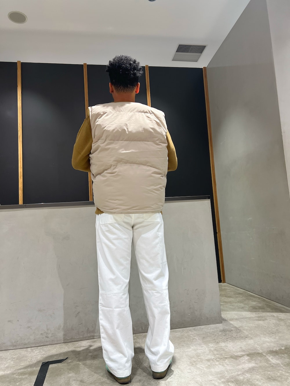 ベージュ系のニット/セーター、グリーン系のダウンベスト、ホワイト系のその他パンツを着用したメンズの秋コーディネートの3枚目の写真