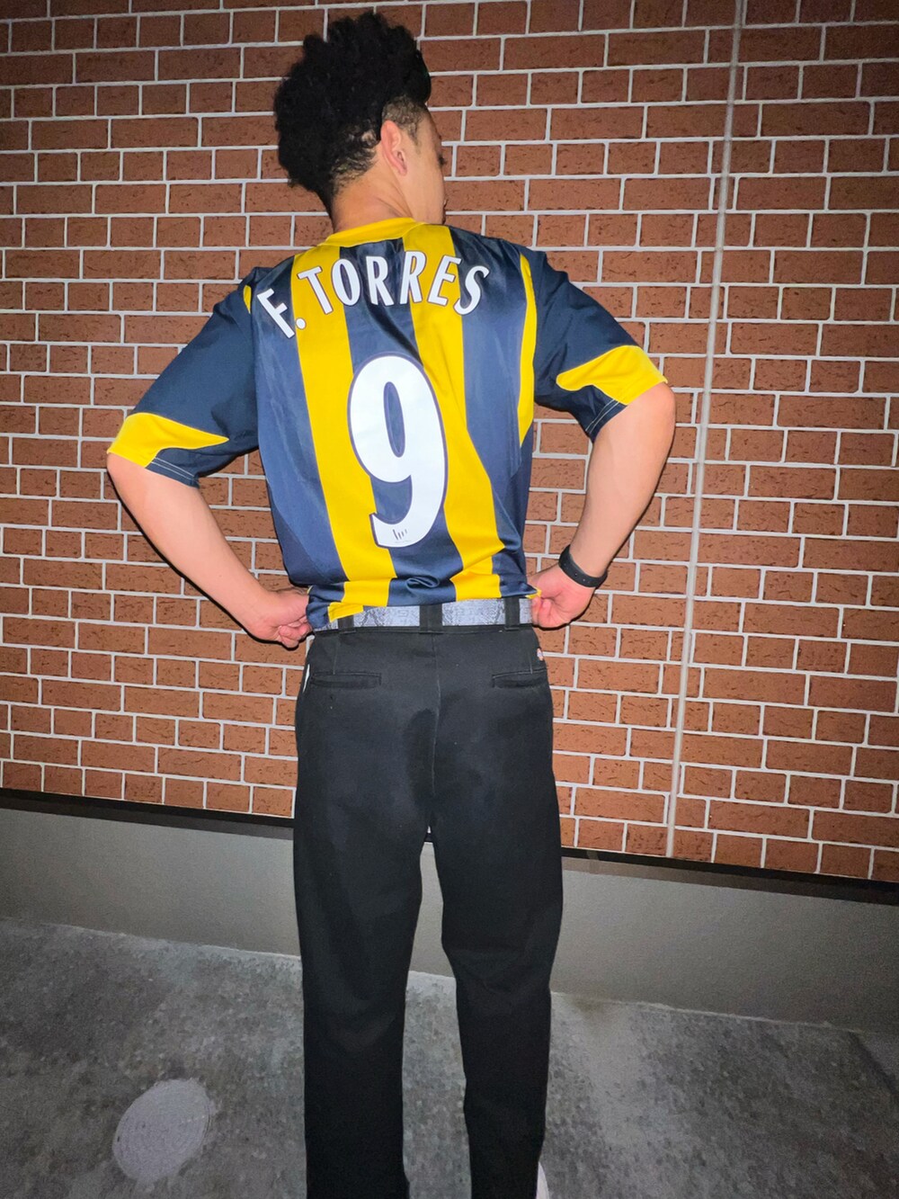 ブラック系のチノパンツ、ホワイト系のスニーカー、イエロー系のジャージを着用したメンズの春コーディネートの3枚目の写真