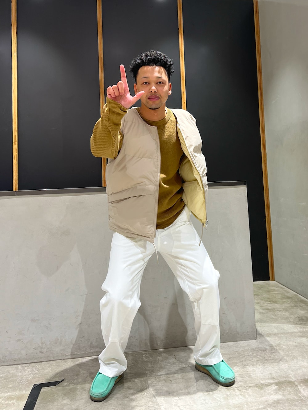 ベージュ系のニット/セーター、グリーン系のダウンベスト、ホワイト系のその他パンツを着用したメンズの秋コーディネートの5枚目の写真