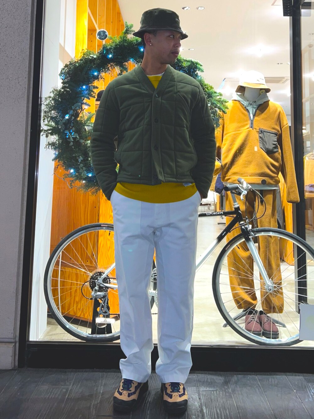 グリーン系のその他アウター、イエロー系のニット/セーター、ブラック系のショルダーバッグを着用したメンズの冬コーディネートの2枚目の写真