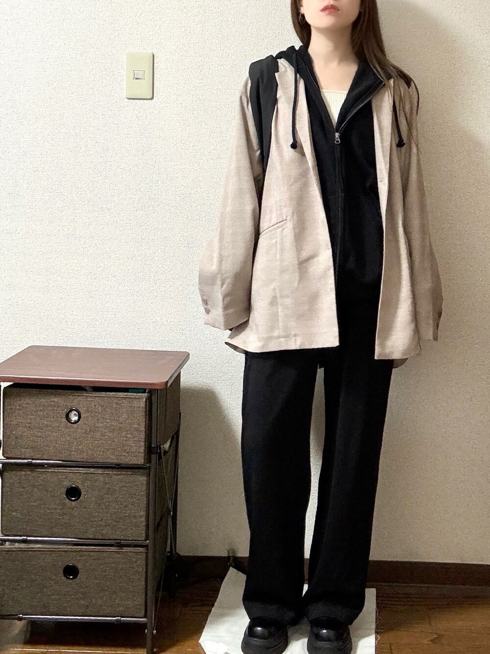 ピンク系のテーラードジャケット、ブラック系のパーカー、ブラック系のスラックスを着用したレディースの秋コーディネートの2枚目の写真