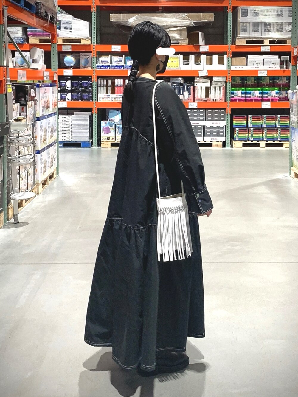 ブラック系のワンピース、ホワイト系のショルダーバッグ、ブラック系のブーツを着用したレディースの春コーディネートの2枚目の写真