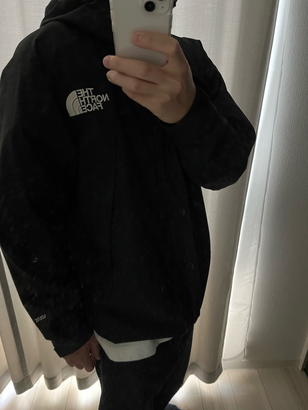 ホワイト系のTシャツ/カットソー、ブラック系のマウンテンパーカー、ブルー系のデニムパンツを着用したメンズの秋コーディネートの2枚目の写真