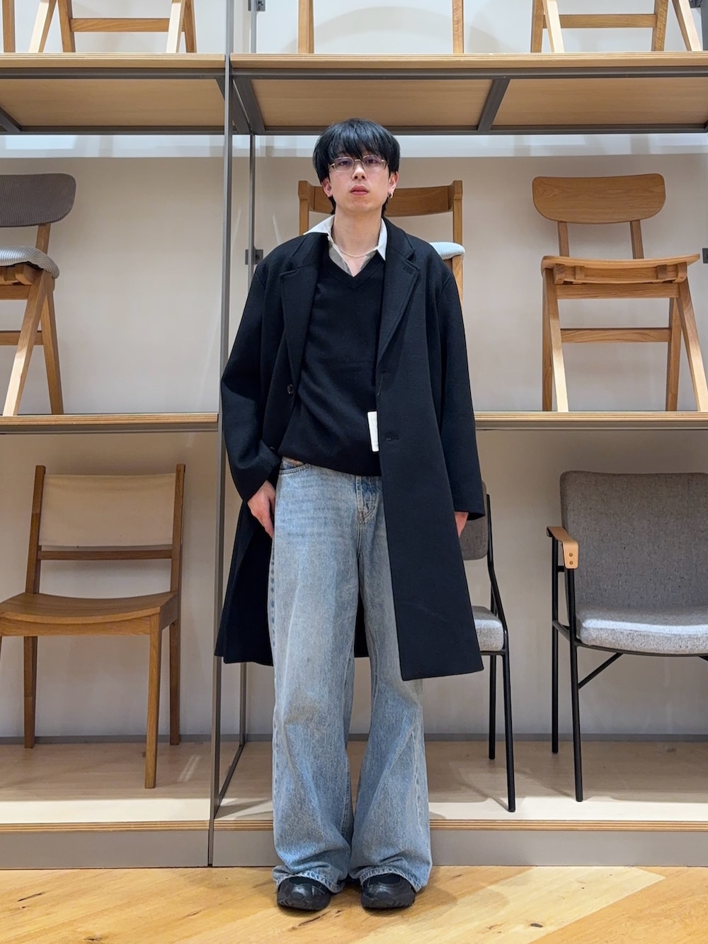 ブラック系のチェスターコート、ブラック系のニット/セーター、ブルー系のデニムパンツを着用したメンズの冬コーディネートの3枚目の写真