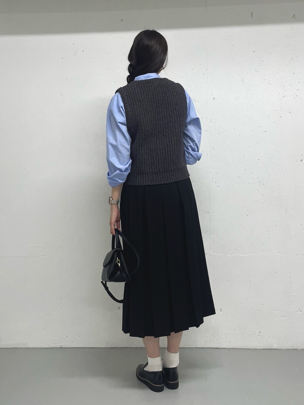 グレー系のベスト、ブルー系のシャツ/ブラウス、ブラック系のスカートを着用したレディースの秋コーディネートの4枚目の写真