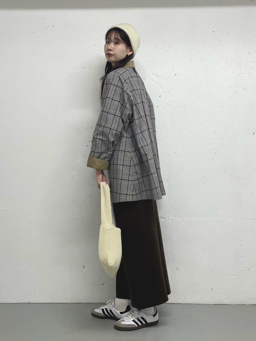 ベージュ系のステンカラーコートを着用したレディースの秋コーディネートの2枚目の写真