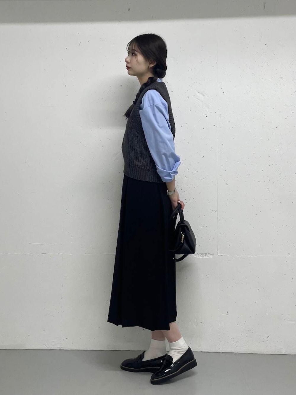 ブルー系のシャツ/ブラウス、グレー系のベスト、ブラック系のスカートを着用したレディースの秋コーディネートの3枚目の写真