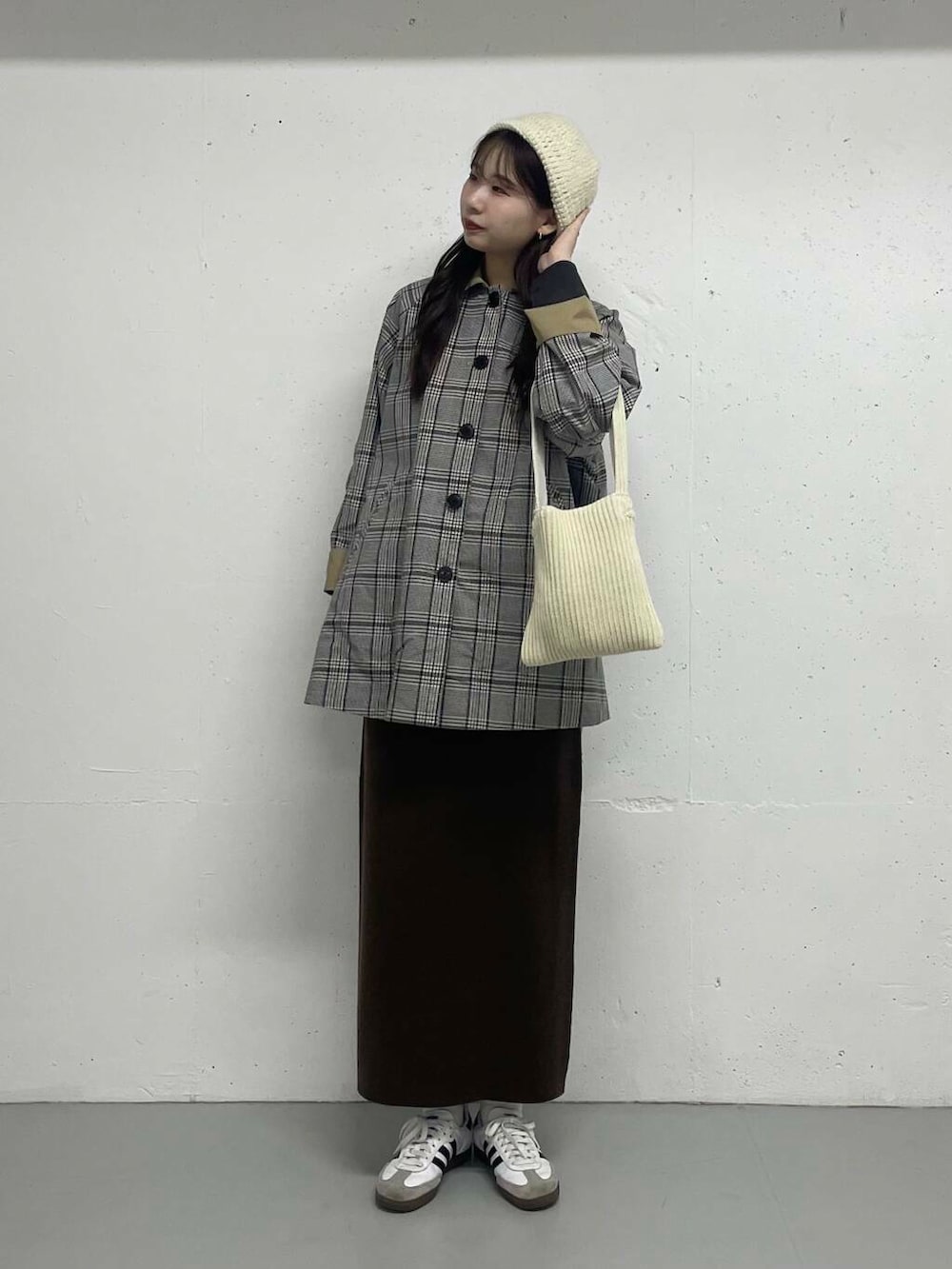 ベージュ系のステンカラーコート、ブラウン系のスカートを着用したレディースの秋コーディネートの3枚目の写真