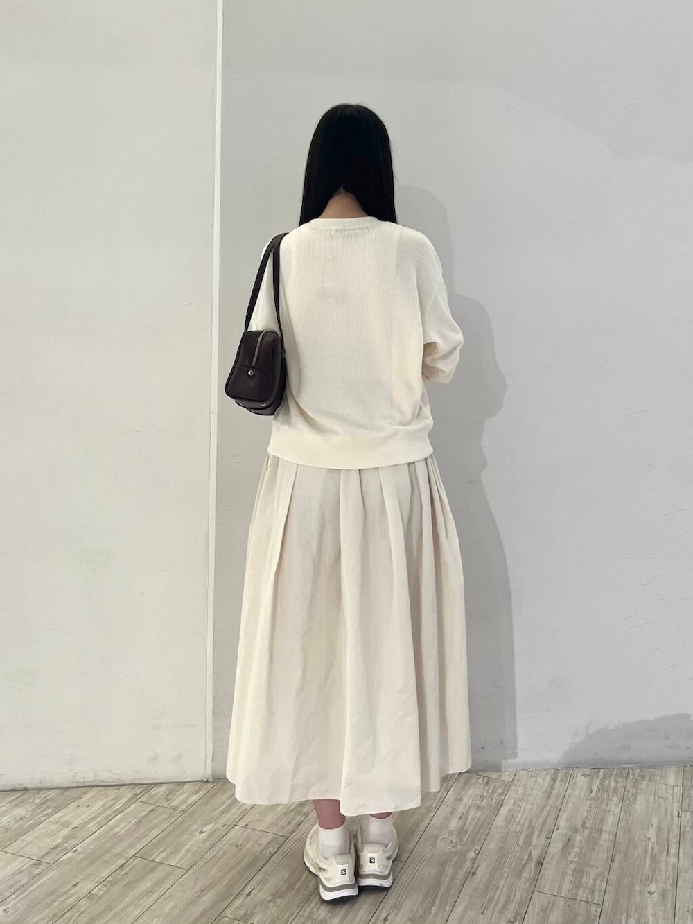 ベージュ系のカーディガン/ボレロ、ホワイト系のスカート、ベージュ系のスニーカーを着用したレディースの秋コーディネートの3枚目の写真