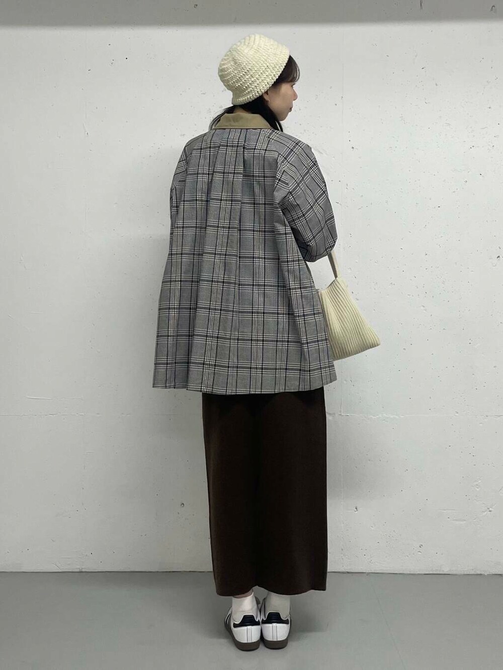 ベージュ系のステンカラーコート、ブラウン系のスカートを着用したレディースの秋コーディネートの4枚目の写真