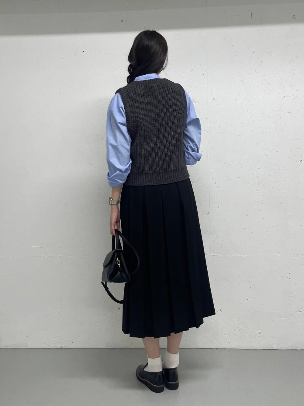 ブルー系のシャツ/ブラウス、グレー系のベスト、ブラック系のスカートを着用したレディースの秋コーディネートの4枚目の写真