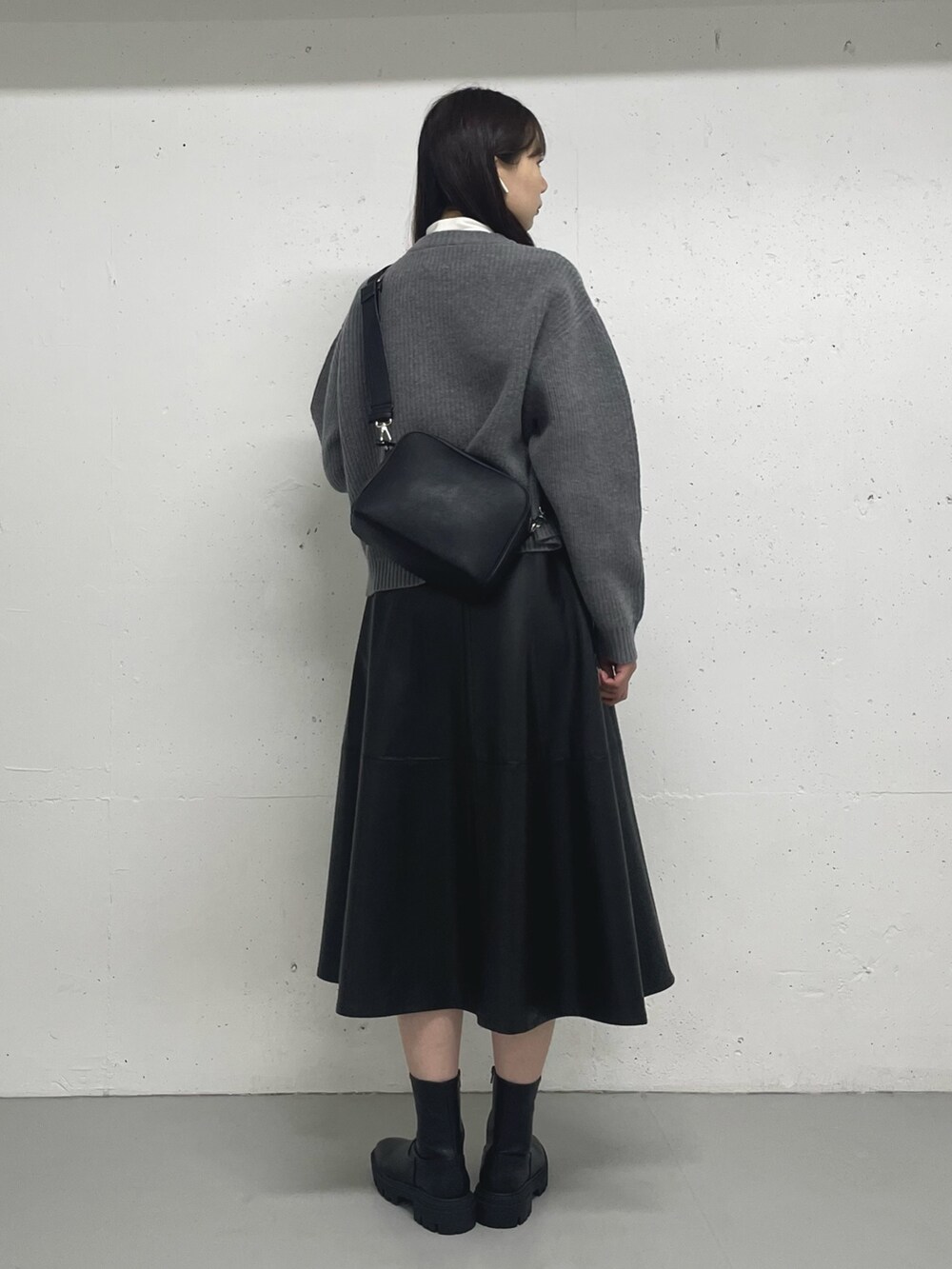 ブラック系のスカート、ホワイト系のTシャツ/カットソー、グレー系のカーディガン/ボレロを着用したレディースの秋コーディネートの4枚目の写真