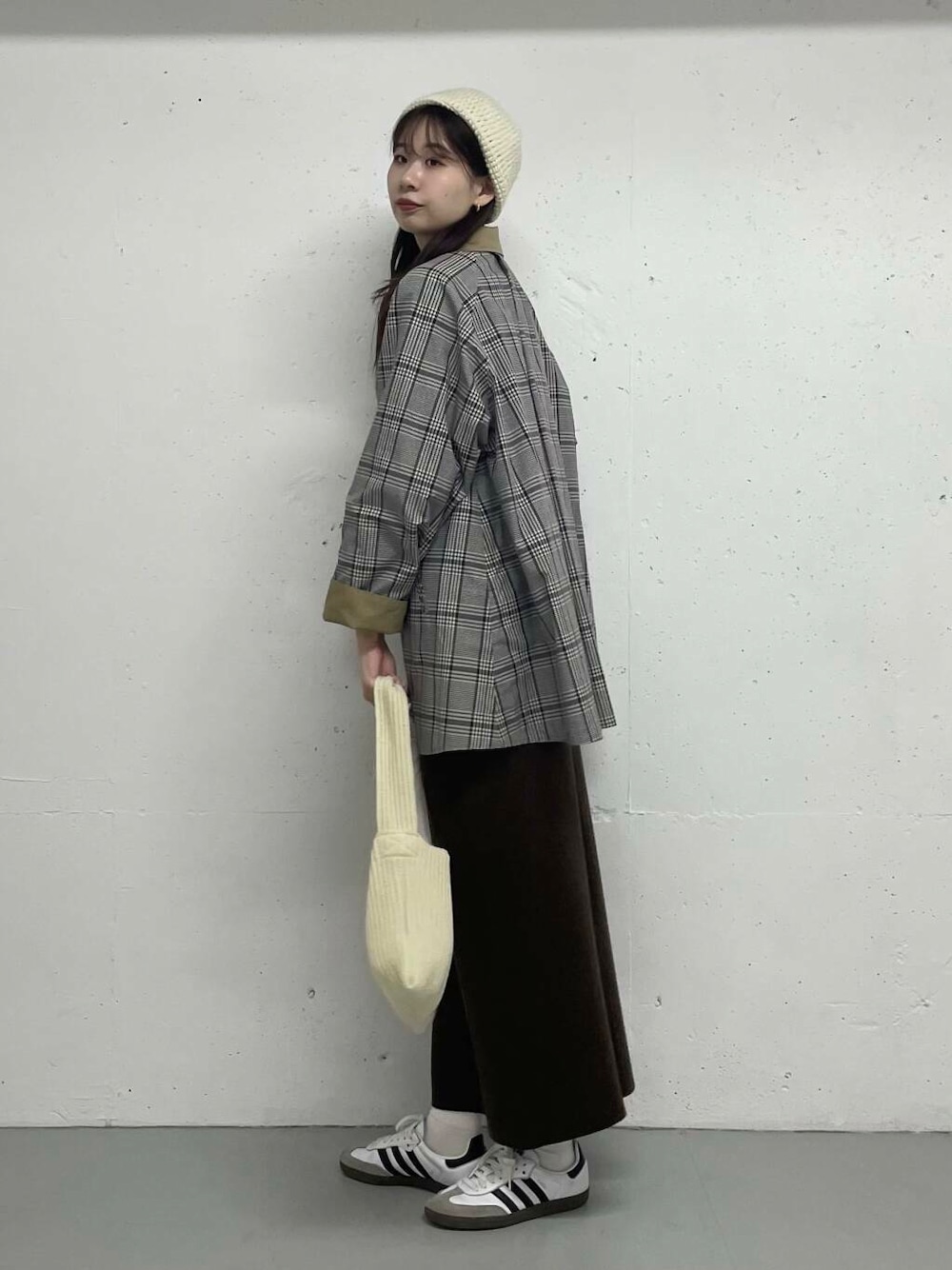 ベージュ系のステンカラーコート、ブラウン系のスカートを着用したレディースの秋コーディネートの2枚目の写真