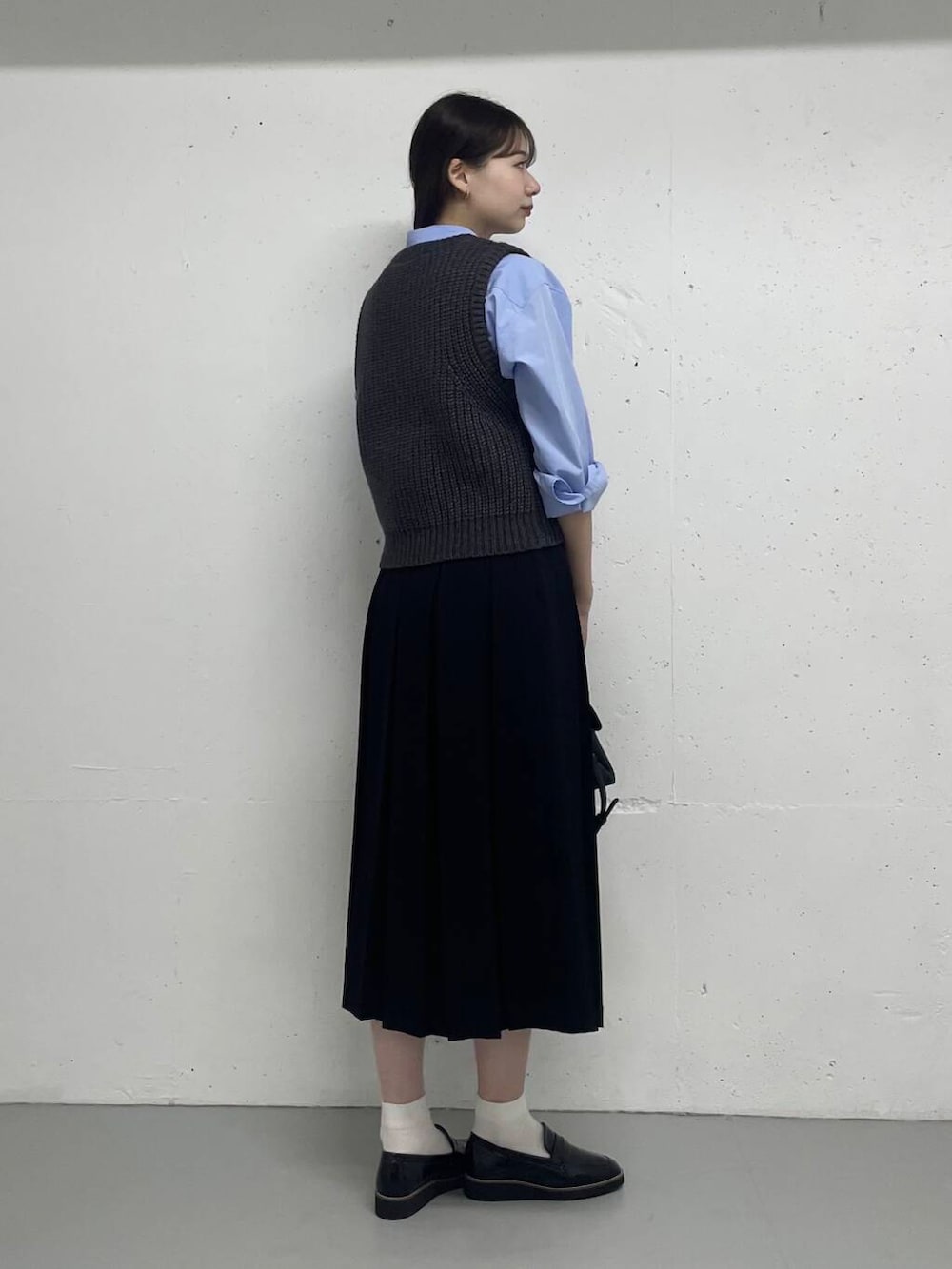 ブルー系のシャツ/ブラウス、グレー系のベスト、ブラック系のスカートを着用したレディースの秋コーディネートの2枚目の写真