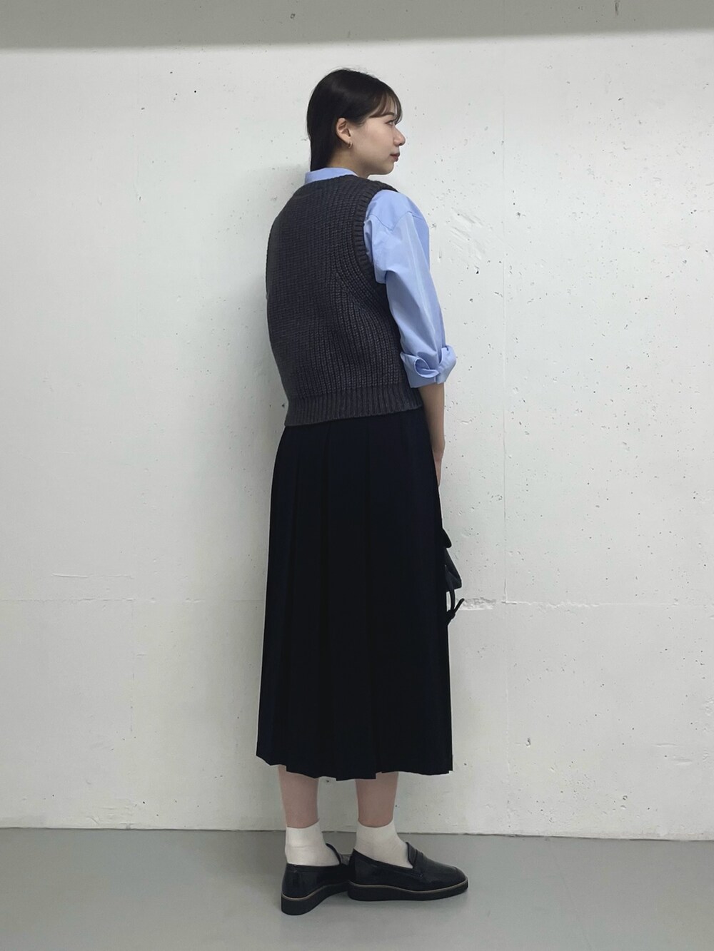 グレー系のベスト、ブルー系のシャツ/ブラウス、ブラック系のスカートを着用したレディースの秋コーディネートの2枚目の写真
