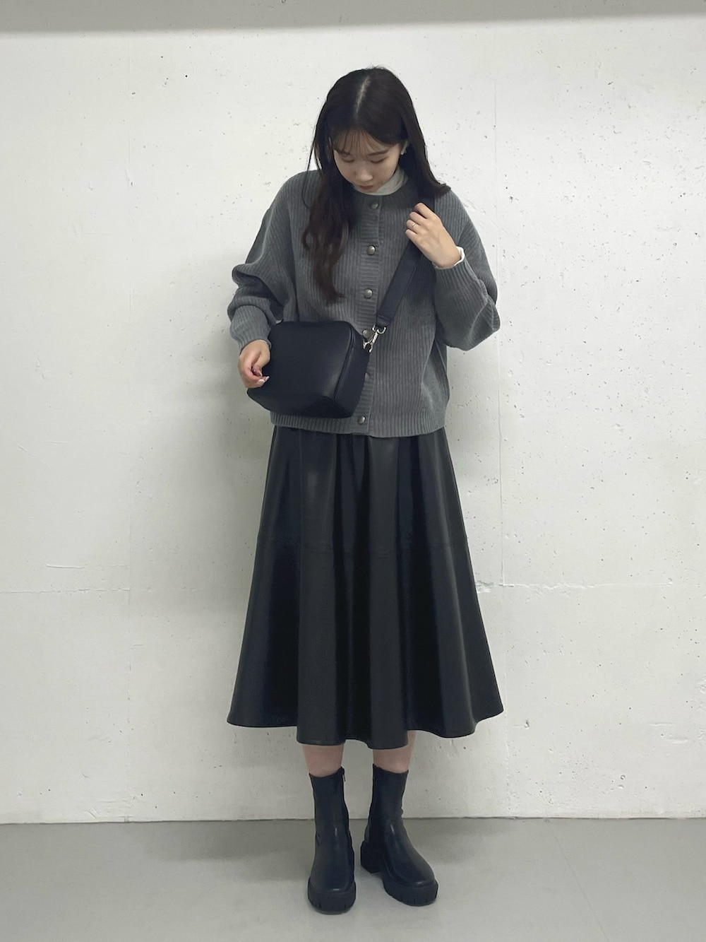 ブラック系のスカート、ホワイト系のTシャツ/カットソー、グレー系のカーディガン/ボレロを着用したレディースの秋コーディネートの3枚目の写真