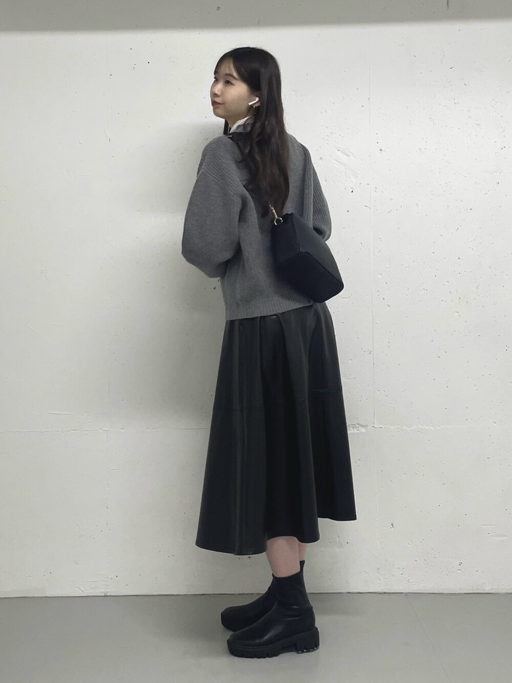 ブラック系のスカート、ホワイト系のTシャツ/カットソー、グレー系のカーディガン/ボレロを着用したレディースの秋コーディネートの2枚目の写真