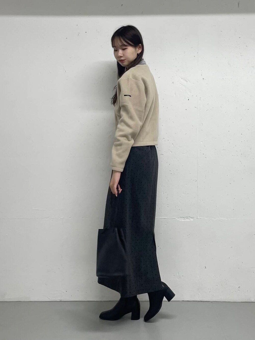 グレー系のTシャツ/カットソー、ベージュ系のカーディガン/ボレロ、グレー系のスカートを着用したレディースの秋コーディネートの2枚目の写真