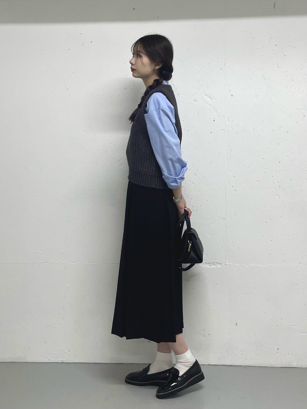 グレー系のベスト、ブルー系のシャツ/ブラウス、ブラック系のスカートを着用したレディースの秋コーディネートの3枚目の写真