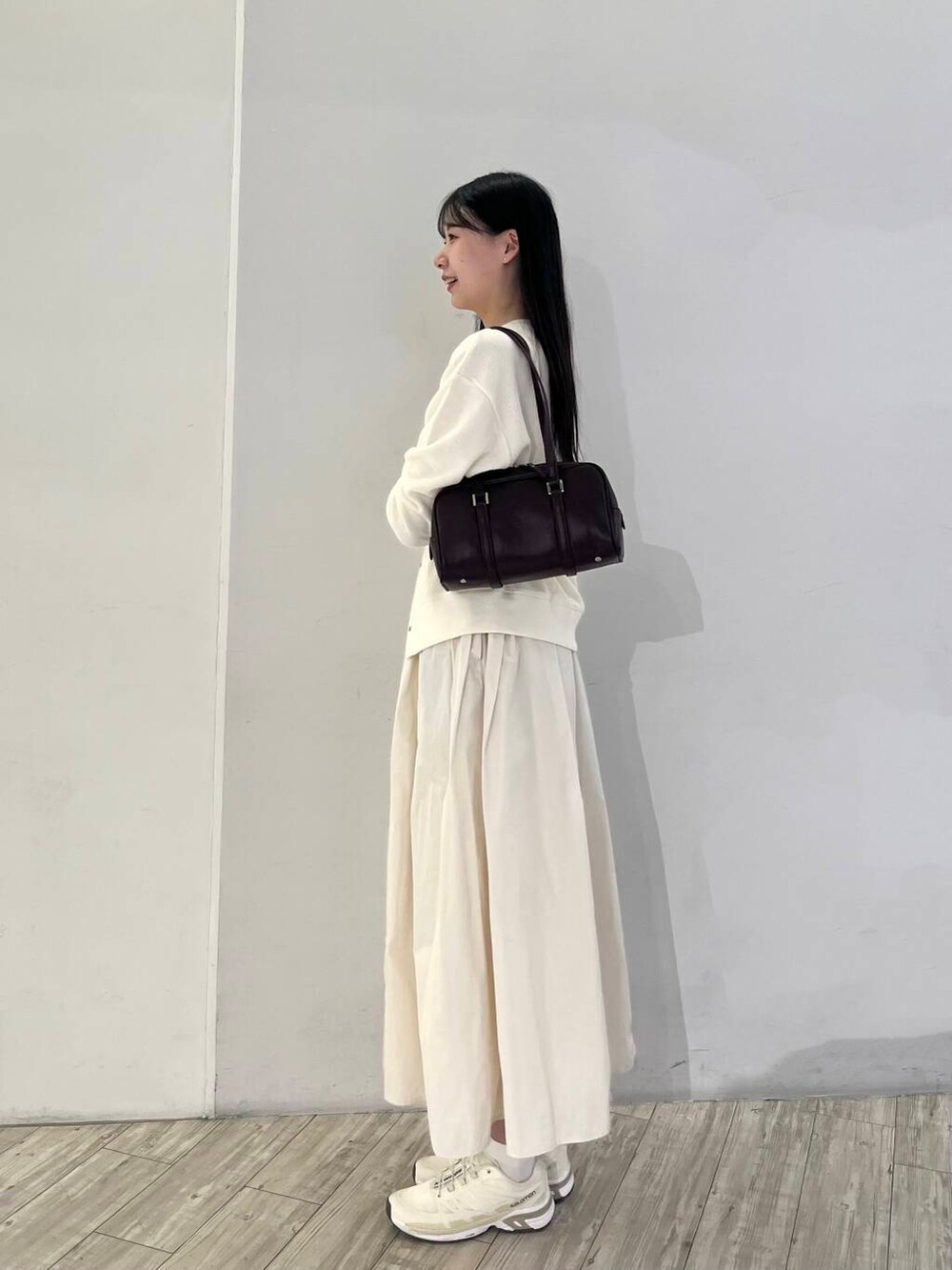 ベージュ系のカーディガン/ボレロ、ホワイト系のスカート、ベージュ系のスニーカーを着用したレディースの秋コーディネートの2枚目の写真