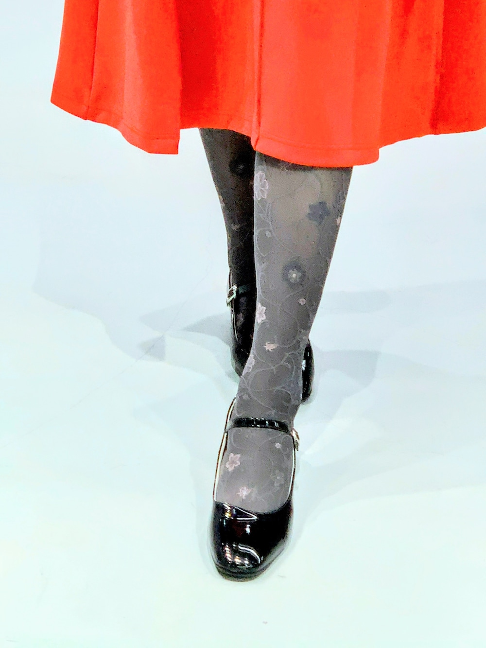 オレンジ系のワンピース、ブラック系のタイツ/ストッキング、グレー系のキャスケットを着用したメンズの春コーディネートの2枚目の写真