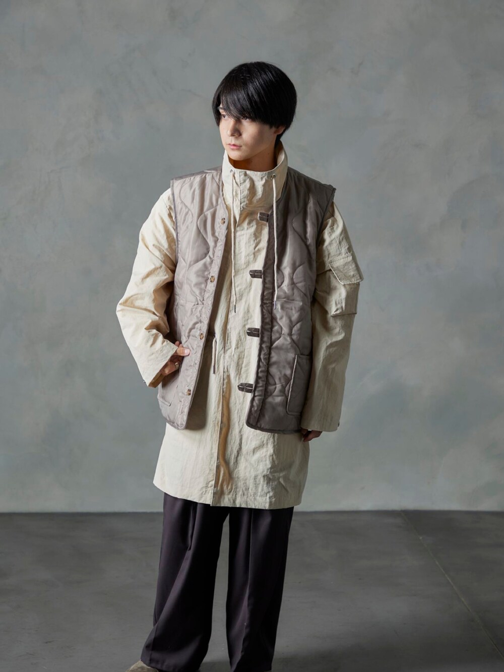 ベージュ系のベスト、ブラウン系のスラックス、ホワイト系のモッズコートを着用したメンズの秋コーディネートの4枚目の写真