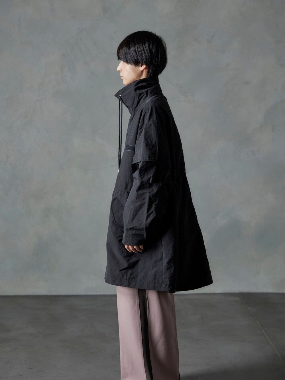 ピンク系のスラックス、ブラック系のモッズコートを着用したメンズの秋コーディネートの2枚目の写真