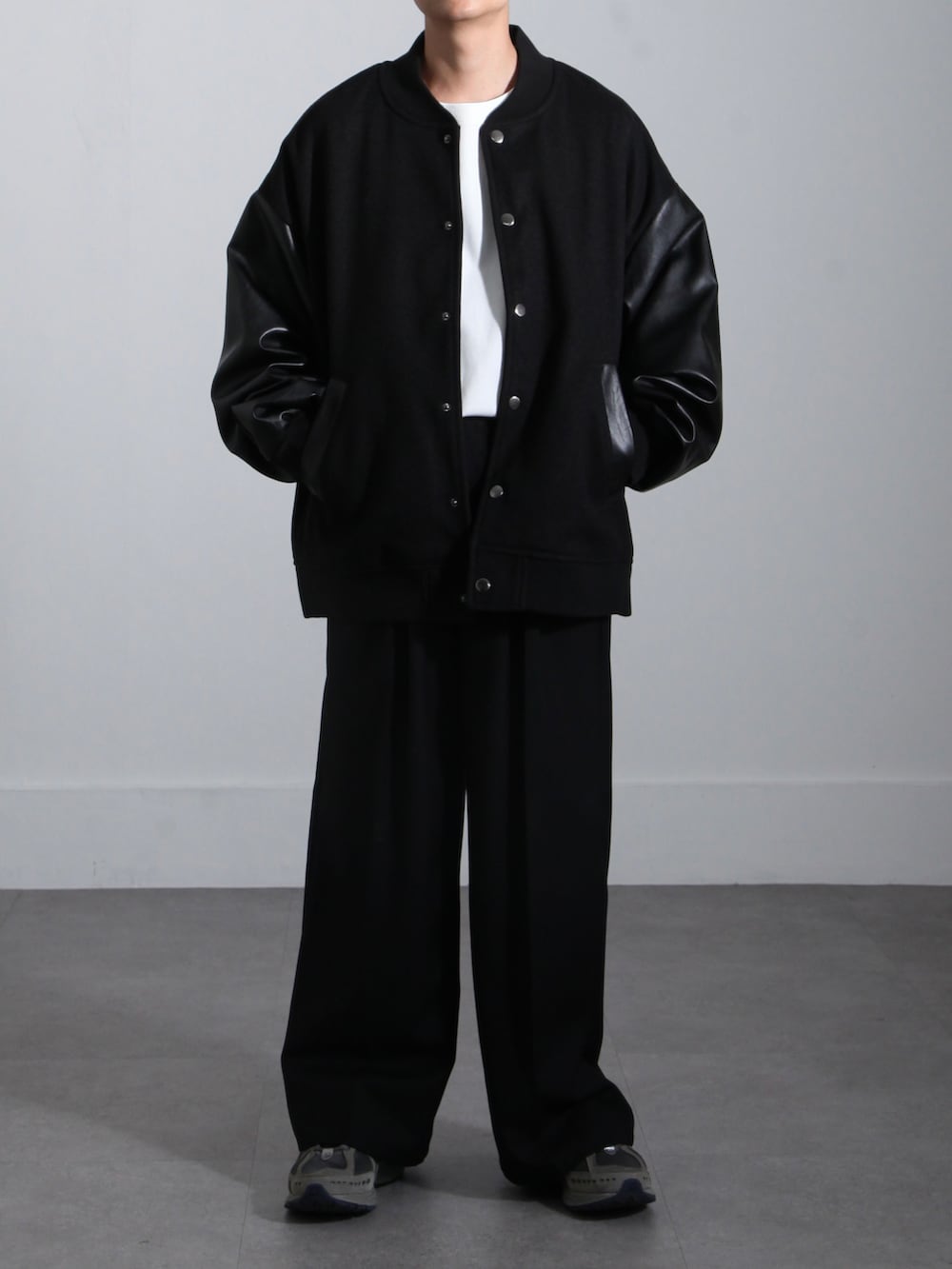 ブラック系のスタジャン、ブラック系のスラックス、ホワイト系のTシャツ/カットソーを着用したメンズの秋コーディネートの2枚目の写真