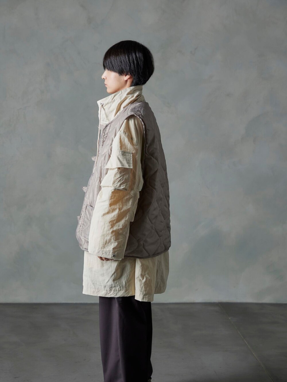 ベージュ系のベスト、ブラウン系のスラックス、ホワイト系のモッズコートを着用したメンズの秋コーディネートの2枚目の写真