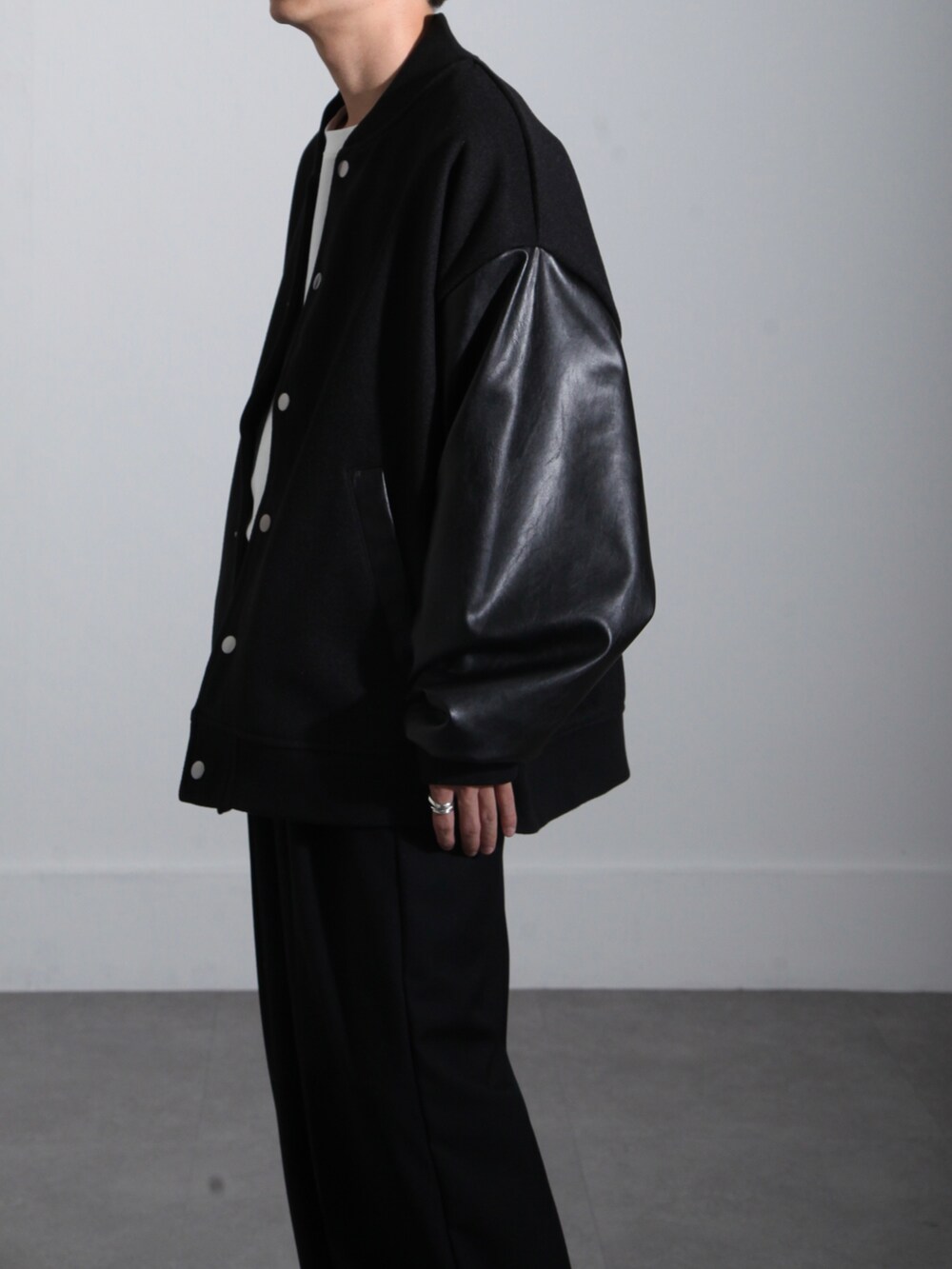 ブラック系のスタジャン、ブラック系のスラックス、ホワイト系のTシャツ/カットソーを着用したメンズの秋コーディネートの4枚目の写真