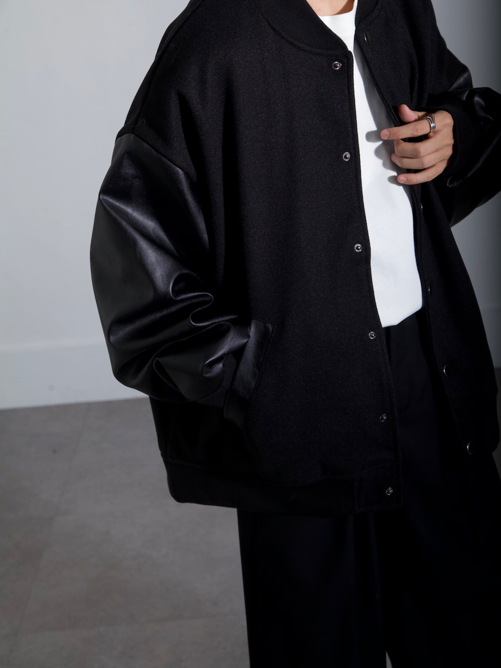 ブラック系のスタジャン、ブラック系のスラックス、ホワイト系のTシャツ/カットソーを着用したメンズの秋コーディネートの3枚目の写真