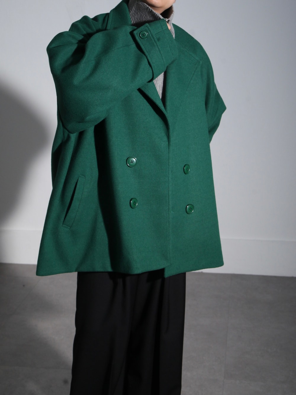 グリーン系のピーコート、グレー系のニット/セーター、ブラック系のスラックスを着用したメンズの秋コーディネートの4枚目の写真