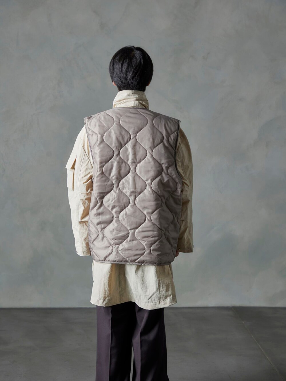 ベージュ系のベスト、ブラウン系のスラックス、ホワイト系のモッズコートを着用したメンズの秋コーディネートの3枚目の写真