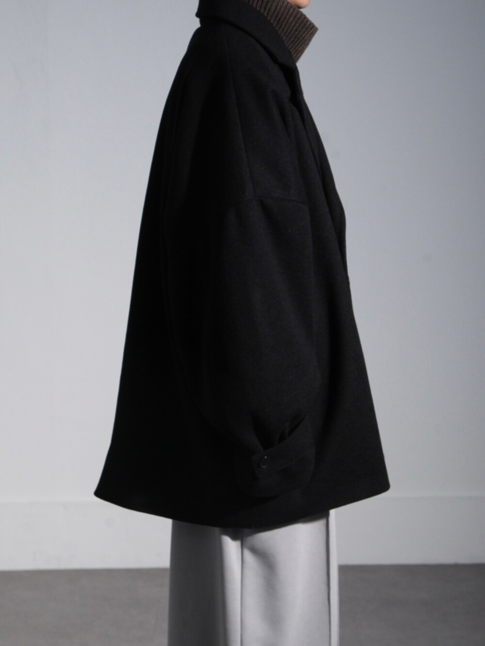 ブラウン系のニット/セーター、ブラック系のピーコート、グレー系のスウェットパンツを着用したメンズの秋コーディネートの2枚目の写真