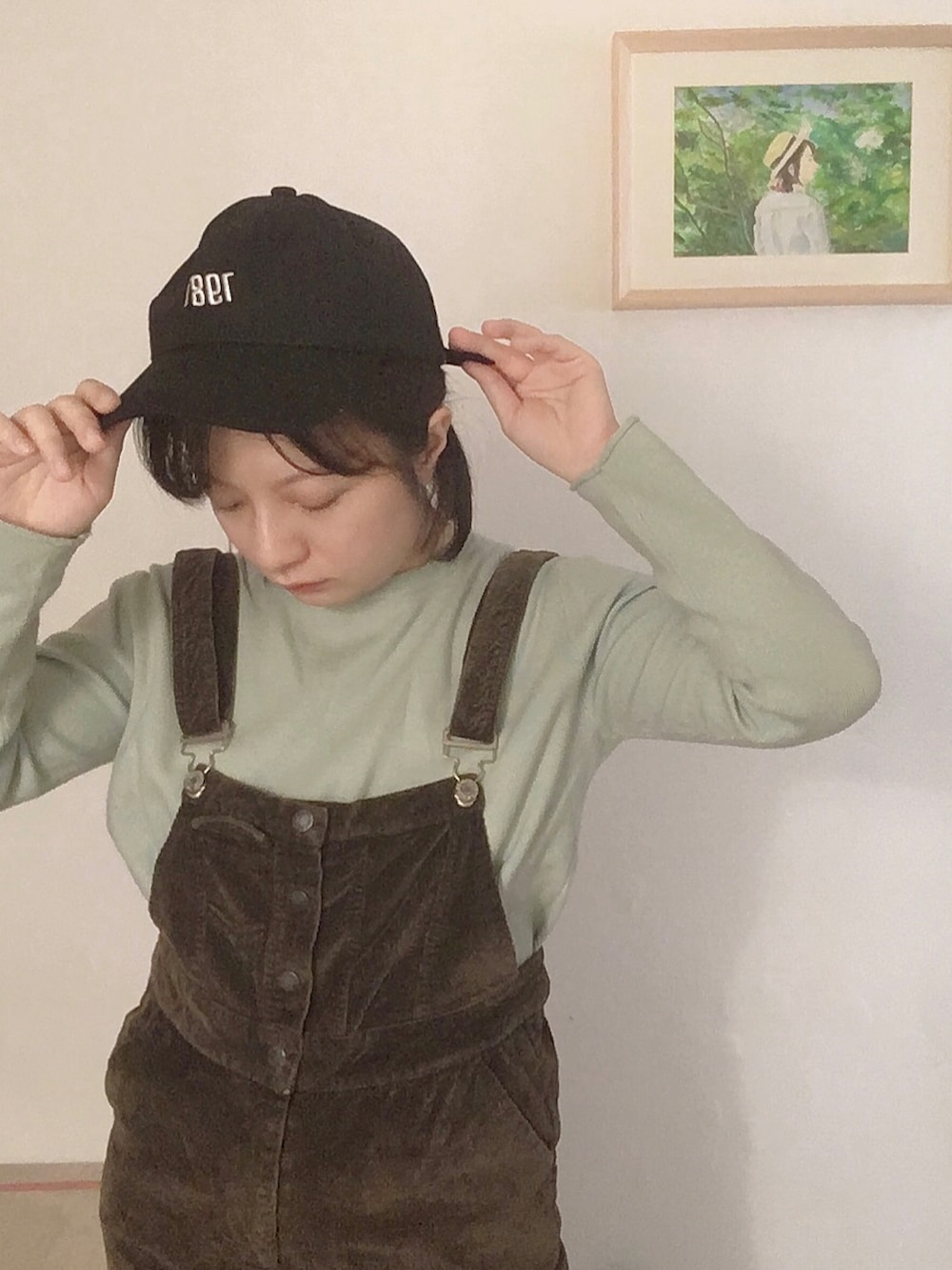 グリーン系のスウェット、ブラウン系のオールインワン・サロペット、ホワイト系のトップスを着用したレディースの秋コーディネートの2枚目の写真