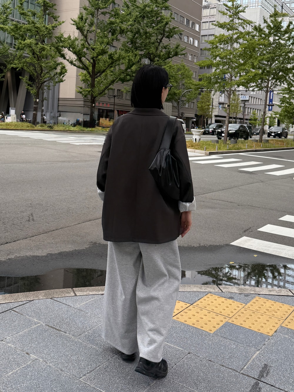 グレー系のテーラードジャケット、ブラック系のキャミソール、グレー系のパンツを着用したレディースの秋コーディネートの3枚目の写真