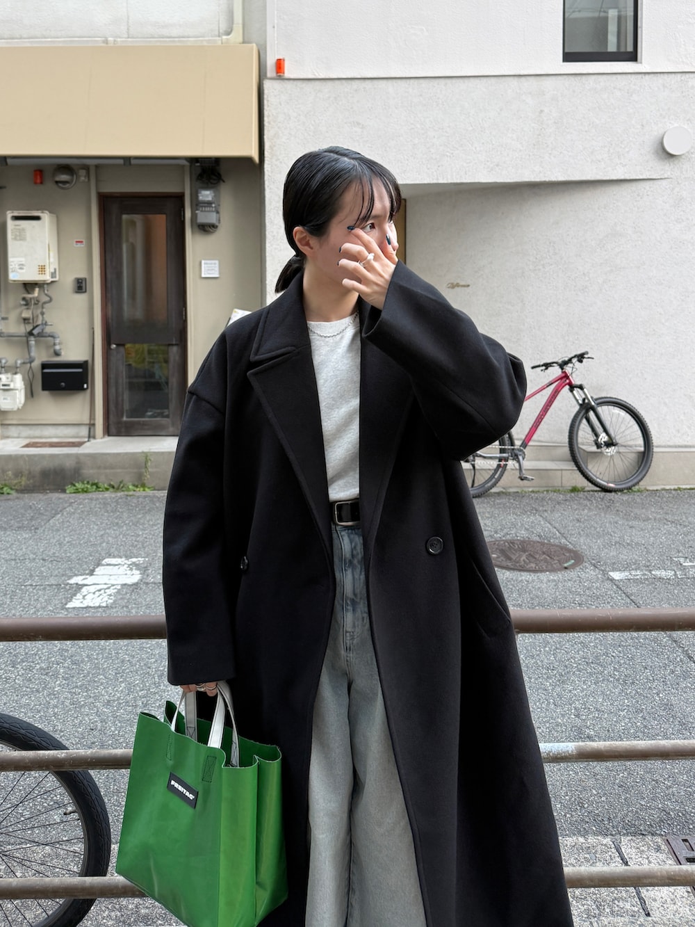 ブラック系のチェスターコート、グレー系のTシャツ/カットソー、ブルー系のデニムパンツを着用したレディースの冬コーディネートの3枚目の写真