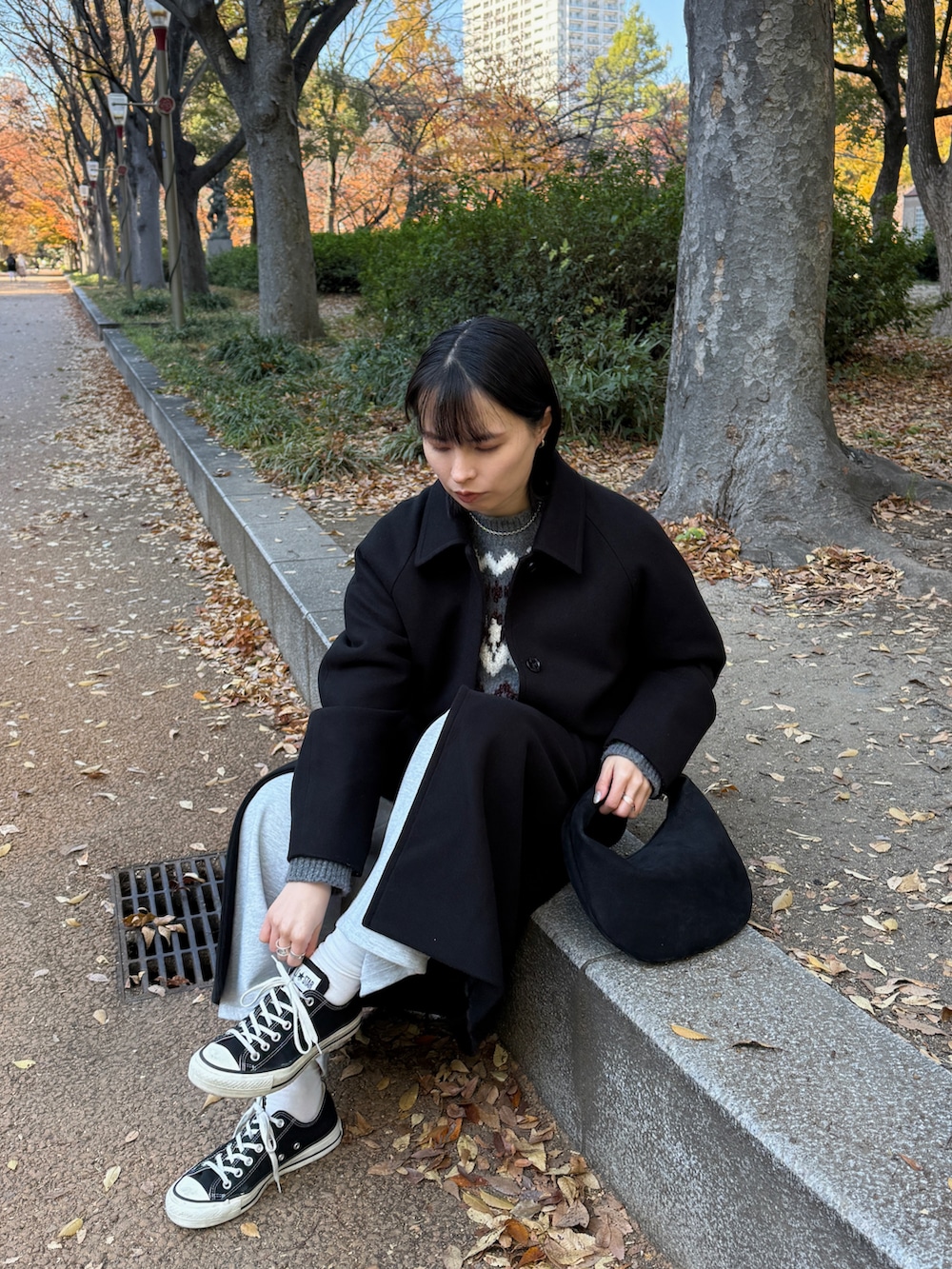 グレー系のパンツ、ブラック系のステンカラーコート、グレー系のニット/セーターを着用したレディースの冬コーディネートの4枚目の写真