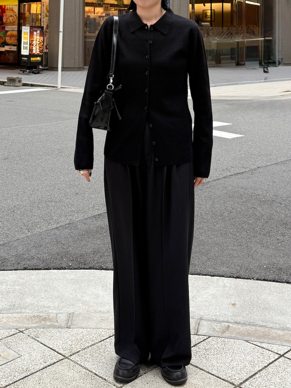 ブラック系のニット/セーター、ブラック系のスラックス、ブラック系のショルダーバッグを着用したレディースの秋コーディネートの3枚目の写真