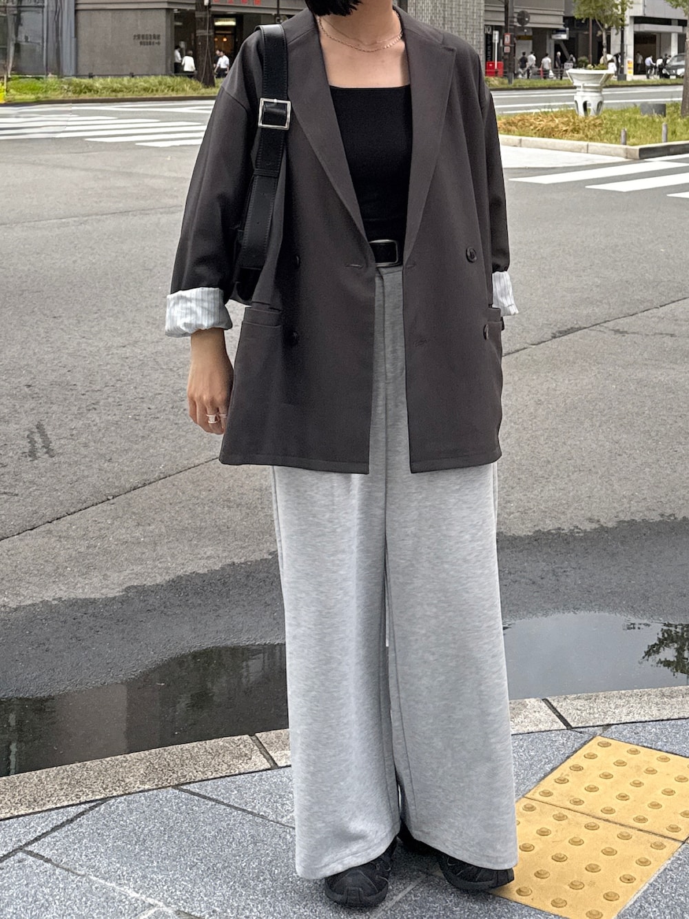 グレー系のテーラードジャケット、ブラック系のキャミソール、グレー系のパンツを着用したレディースの秋コーディネートの2枚目の写真
