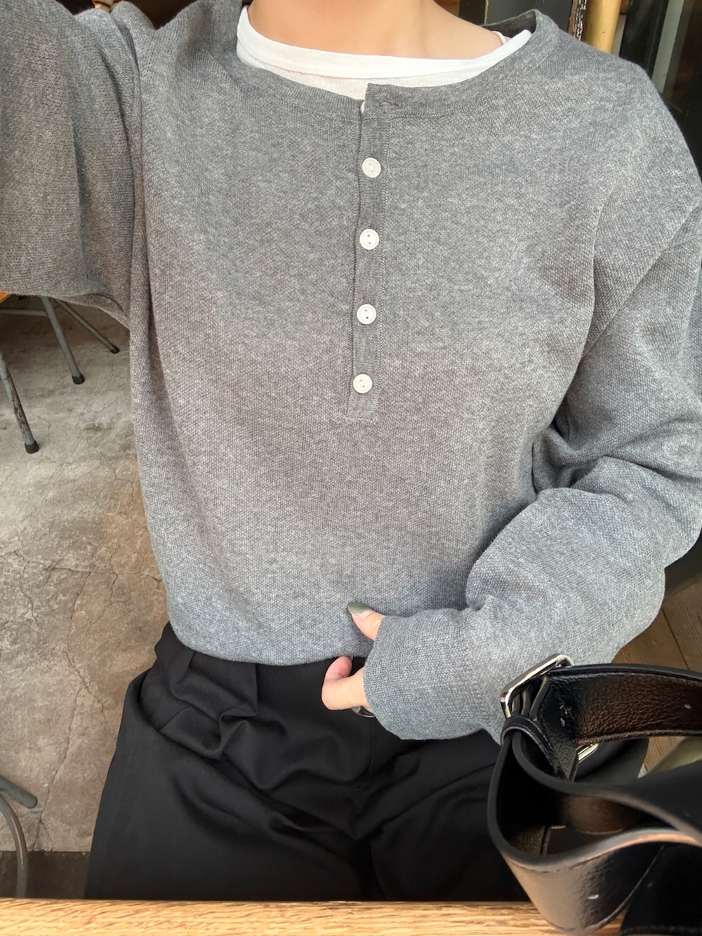 グレー系のニット/セーター、ブラック系のTシャツ/カットソー、ブラック系のショルダーバッグを着用したレディースの秋コーディネートの3枚目の写真