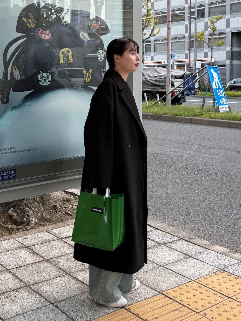 ブラック系のチェスターコート、グレー系のTシャツ/カットソー、ブルー系のデニムパンツを着用したレディースの冬コーディネートの4枚目の写真