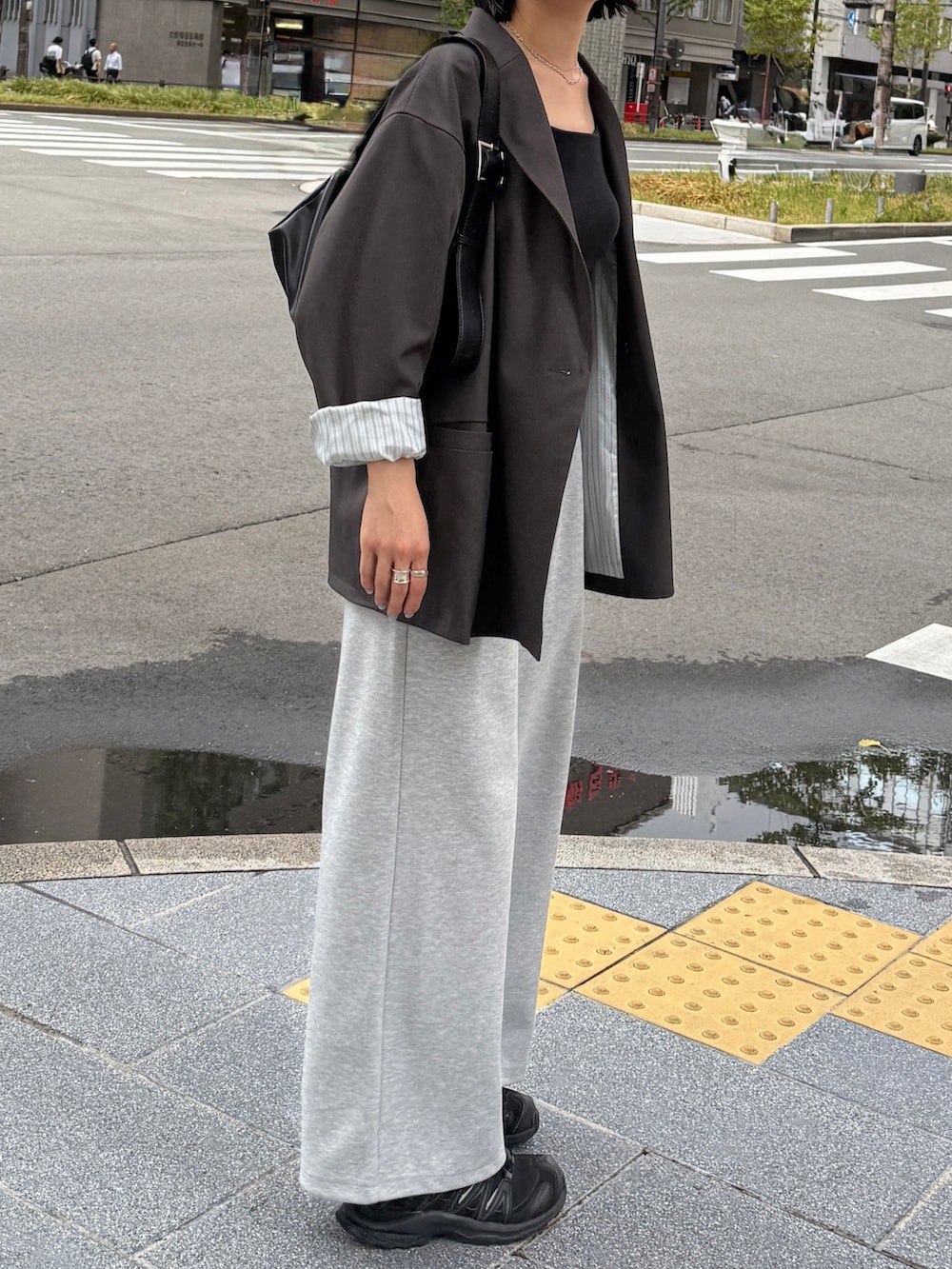 グレー系のテーラードジャケット、ブラック系のキャミソール、グレー系のパンツを着用したレディースの秋コーディネートの4枚目の写真